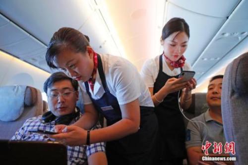 資料圖：乘務(wù)員們在客艙內(nèi)為旅客調(diào)試機上上網(wǎng)功能。<a target='_blank' ><p  align=